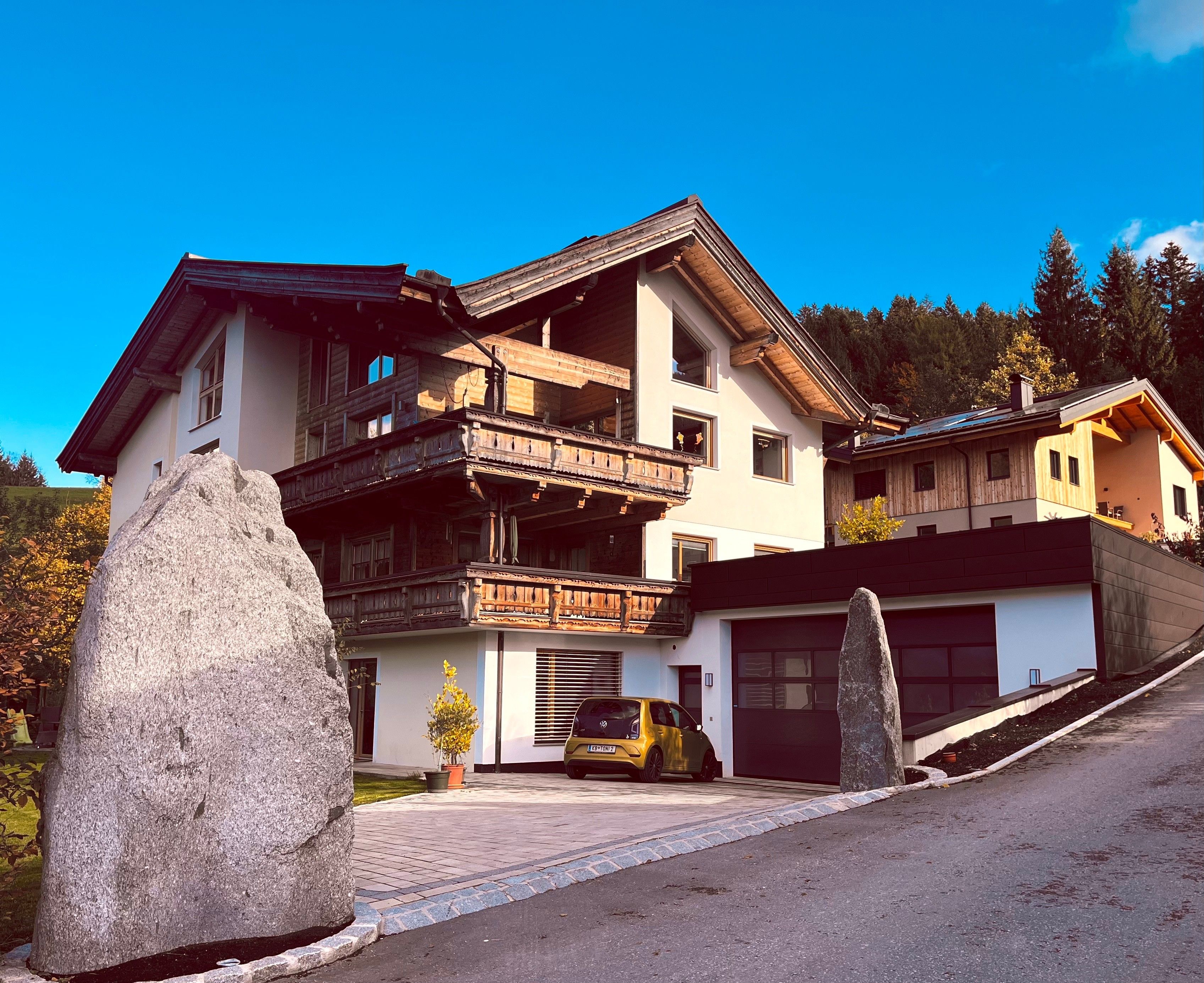 Una casa a due piani con un balcone, un garage e una strada privata.
