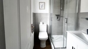 A modern bathroom with a toilet, a shower enclosure, and a sink. - Canterbury Charm - Spacious 4 Bedroom House (Canterbury)