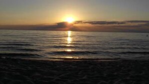 Tramonto sul mare calmo con orizzonte sereno.