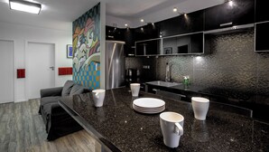 A modern kitchen with a black granite countertop, stainless steel appliances, and a colorful abstract painting on the wall. - RentPlanet - Jedności Narodowej (Wrocław)