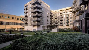 A modern apartment building with multiple balconies, a well-maintained garden, and a clear sky. - RentPlanet - Jedności Narodowej (Wrocław)