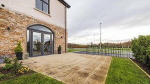 A modern house with a stone facade, a glass door entrance, and a paved patio.