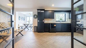 Una cocina moderna con muebles oscuros, lavavajillas y ventana.
