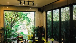 A modern interior with large windows, a seating area, and a refrigerator. - Family Home Villa Nearby Ba Na Hills (Đà Nẵng)