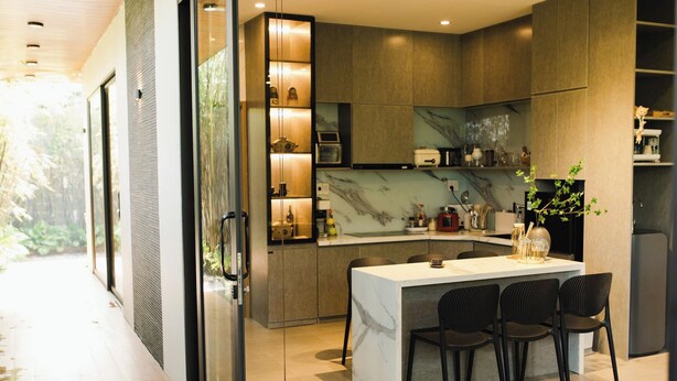 A modern kitchen with a marble countertop, built-in appliances, and a dining area with four chairs. - Family Home Villa Nearby Ba Na Hills (Đà Nẵng)