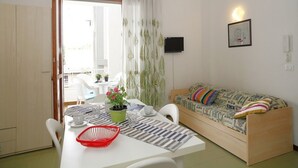 Ein gemütlicher Wohnbereich mit Essplatz, einer Couch und einem Fernseher.