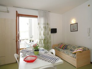 Ett kompakt bostadsutrymme med en matplats, en soffa och en tv.