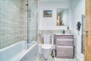 Un baño moderno con ducha envuelta en cristal, inodoro y tocador con espejo.