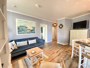 A living room with a sofa, a small table, and a dining area with chairs. - Ostseestrand-14, ideal location on the beach, 2 balconies with ocean views, elevator, sauna (Kühlungsborn)