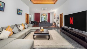Uma sala de estar moderna com um sofá cinzento, uma mesa de centro de madeira e uma televisão de tela plana com o logotipo da Netflix.