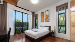 Quarto de hotel moderno com uma cama grande, uma escrivaninha e vista para o verde pelas janelas.