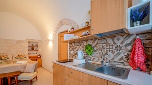 Eine moderne Küche mit Holzschränken, einer Edelstahlspüle und einer zurückliegenden Wand mit Musterdesign.