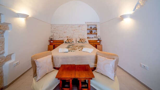 Ein Schlafzimmer mit Bett, Nachttischen, einer hölzernen Bank und einer Steinwand.