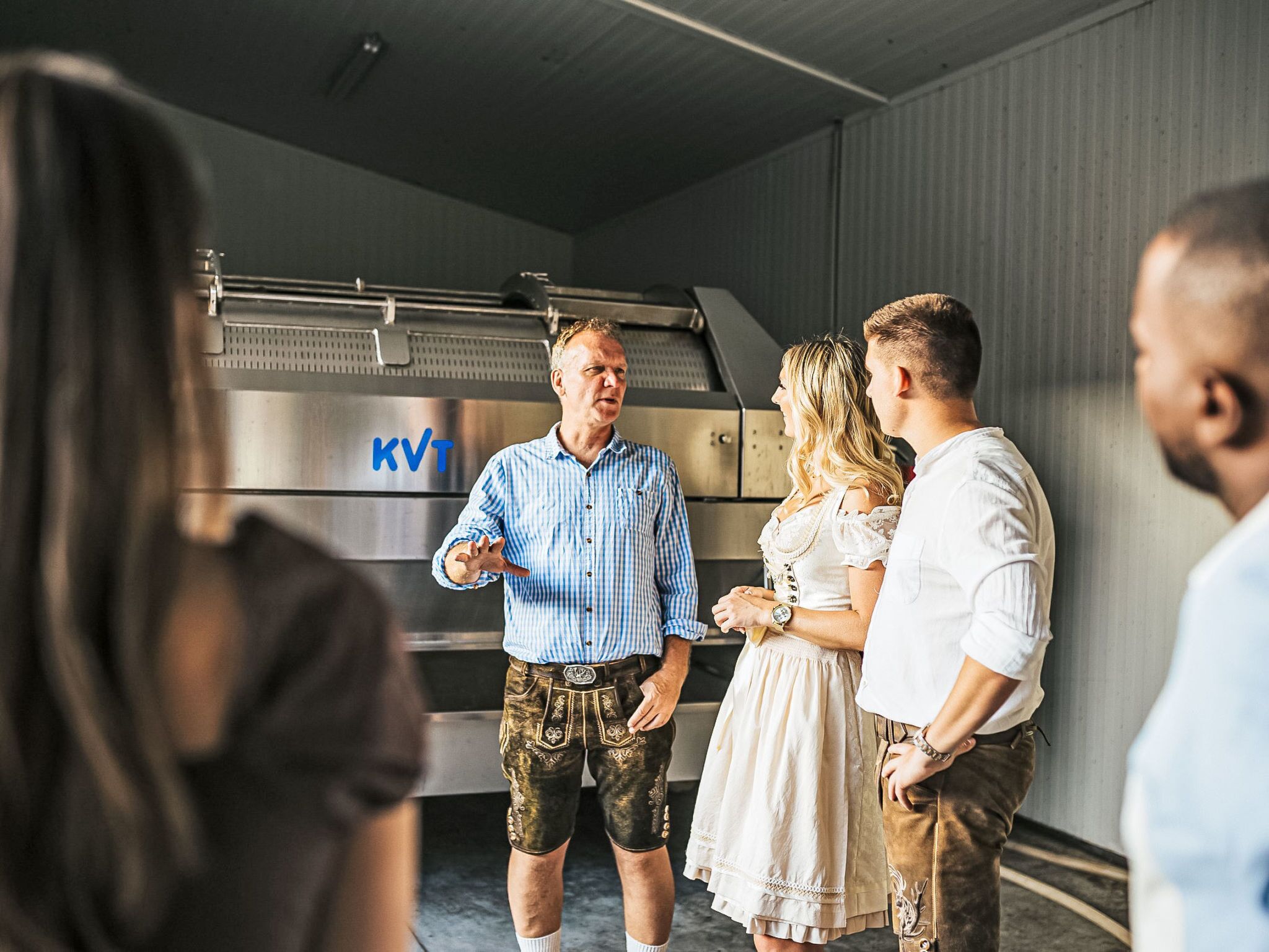 Un groupe de personnes se tient devant une grande machine industrielle portant le logo « KVT ».
