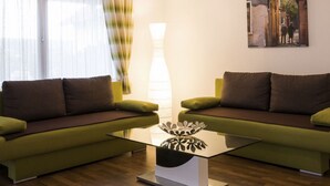 A modern living room with two green sofas, a glass coffee table, and a painting on the wall. - mit Garten, Grill und Terrasse by Interhome (Hagenbrunn)