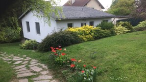 A white house with a stone pathway leading to the front door, surrounded by a well-maintained garden with various flowers and shrubs. - mit Garten, Grill und Terrasse by Interhome (Hagenbrunn)