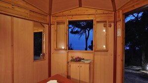 A wooden room with a bed, a small table with a mirror, and a window with a view of trees. - TCI Isole Tremiti (Tremiti Islands)