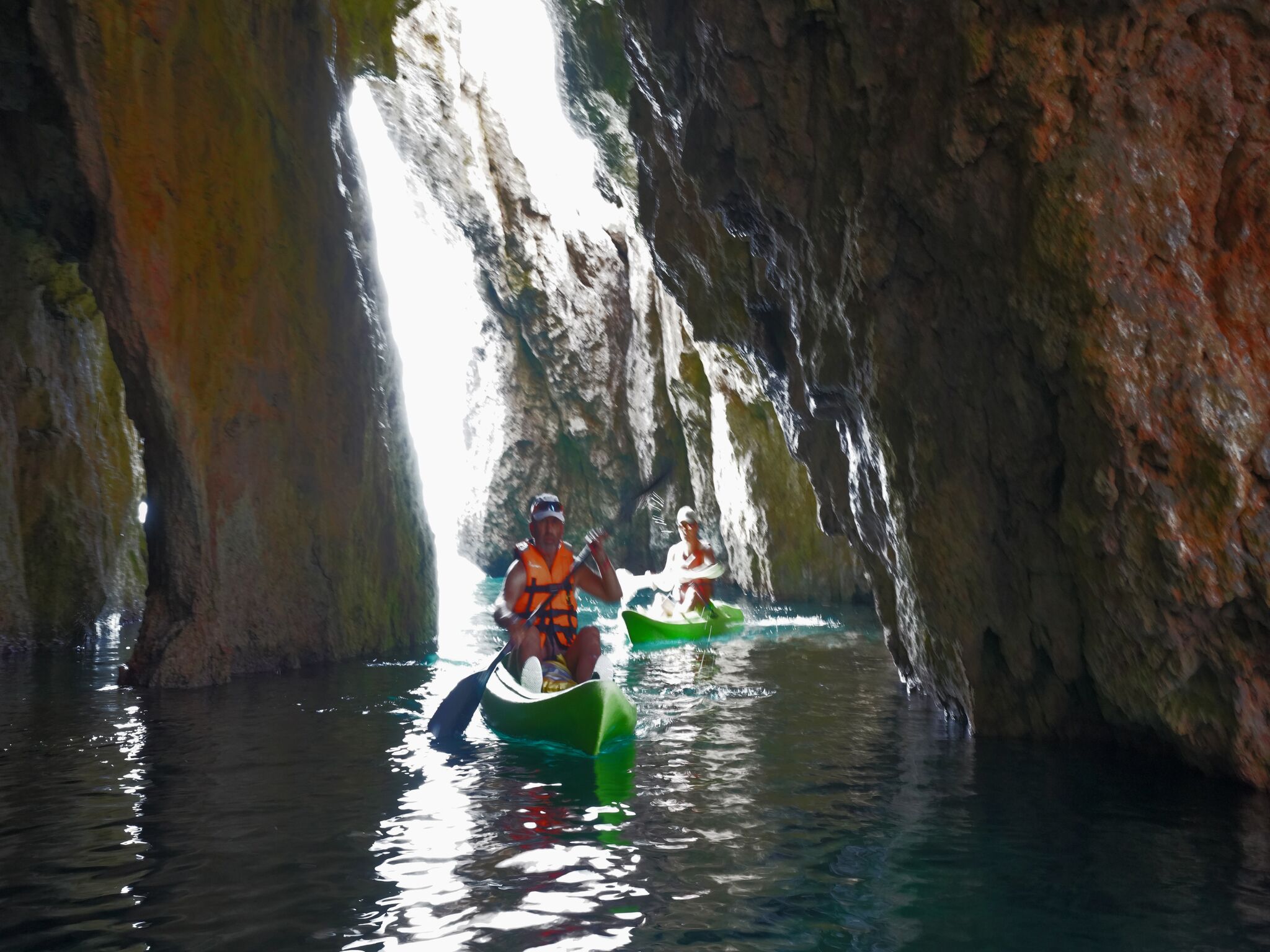 Deux kayaks naviguent dans un étroit chenal rocheux, bordé de formations rocheuses naturelles de chaque côté.