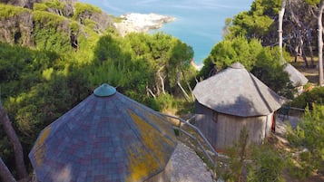 Vista di una zona costiera con due capanne dal tetto di paglia, immerse nel verde e con vista sul mare.