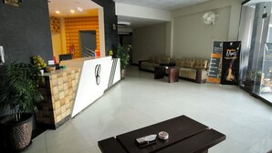 Una hall d'albergo con reception, zona salotto e una ventola a muro.