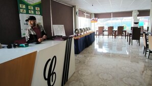 Un'area di accoglienza con un bancone, una sveglia e uno schermo televisivo.