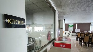 A restaurant interior with a 'KITCHEN' sign, a counter, and dining tables.