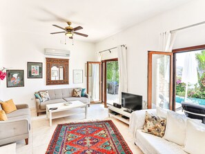 A living room with a sofa, coffee table, TV, and a patterned rug. - mit Blick auf das Wasser by Interhome (Kalkan)