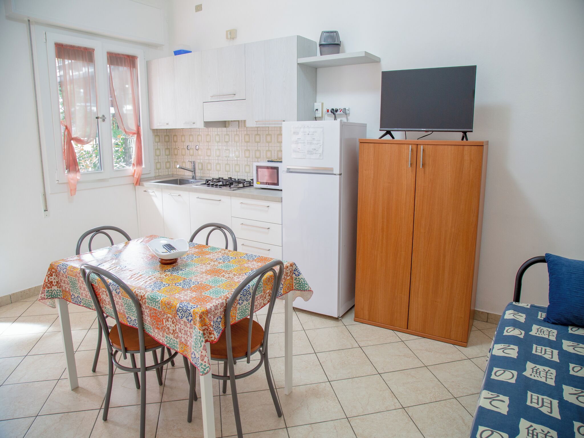 A compact kitchen with white cabinets, a microwave, a stove, and a wooden cabinet.