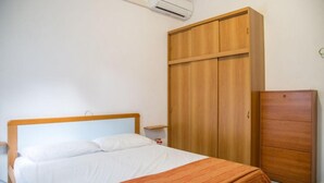 Une chambre à coucher avec un lit, une armoire en bois et un appareil de climatisation.