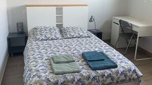 A neatly arranged bedroom with a bed, a desk, and a chair. - 1st floor apartment 5 min from town center and 15 min from beaches. (Lannion)