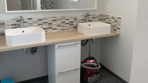 A bathroom with two sinks, a large mirror, and a towel rack. - 1st floor apartment 5 min from town center and 15 min from beaches. (Lannion)