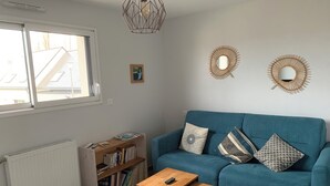 A living room with a blue sofa, two wooden tables, a bookshelf, and two wall-mounted mirrors. - 1st floor apartment 5 min from town center and 15 min from beaches. (Lannion)