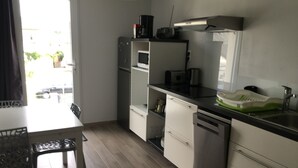 A modern kitchen with a dining table, cabinets, and a coffee maker. - 1st floor apartment 5 min from town center and 15 min from beaches. (Lannion)