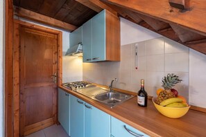 A kitchen with a wooden countertop, a gas stove, a sink, and a bowl of fruit. - Cozy apartment with furnished patio (San Teodoro)