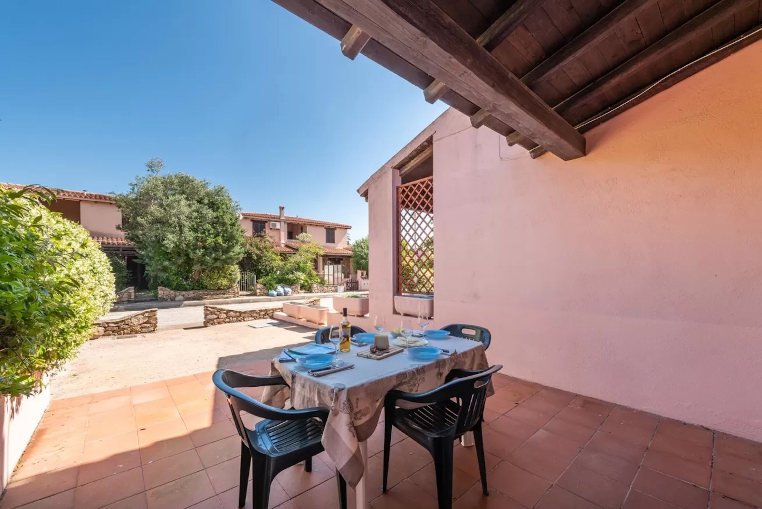 An outdoor patio with a table set for dining, surrounded by stone walls and greenery.