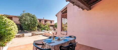 An outdoor patio with a table set for dining, surrounded by stone walls and greenery.