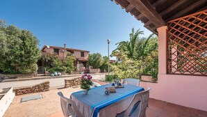A patio with a table and chairs, a potted plant, and a view of a residential area with houses and trees. - Perfectly located flat in San Teodoro (San Teodoro)