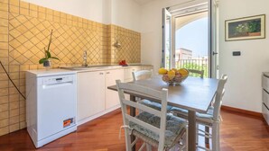 Una cocina compacta con lavavajillas, un lavabo y una mesa de comedor con sillas. Se aprecia una ventana con vistas al exterior.