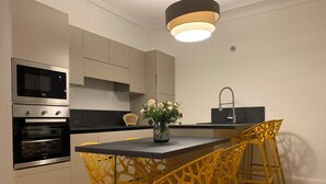 Eine moderne Küche mit integrierten Geräten, einer zentralen Kochinsel mit Stühlen und einer Vase mit Blumen.
