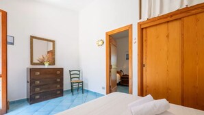 Een slaapkamer met een bed, een houten dressoir, een stoel en een kledingkast.
