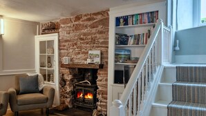 A cozy living room with a stone fireplace, a bookshelf, and a staircase. - Stunning  villa for 8 people with WIFI (Cawsand)