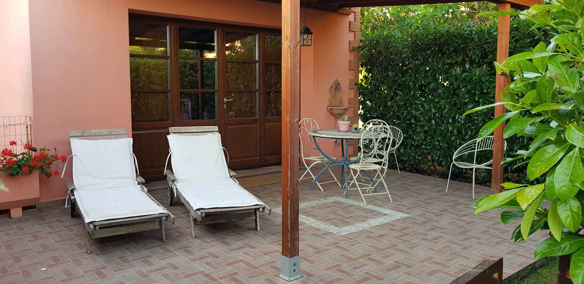Un patio con due lettini prendisole, un tavolo in metallo e sedie.