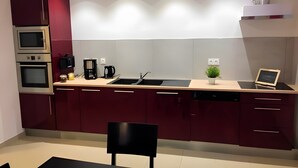 Een moderne keuken met inbouwapparatuur, een spoelbak en een eethoek met een stoel.