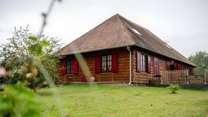 Een houten huis met een schuin dak en een omheinde tuin.