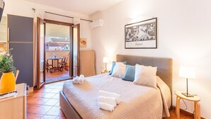 Habitación de hotel con cama, lámparas de noche, un cuadro en la pared y vistas al balcón exterior.