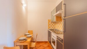 Cocina compacta con una mesa de comedor para dos personas, refrigerador, horno y microondas.