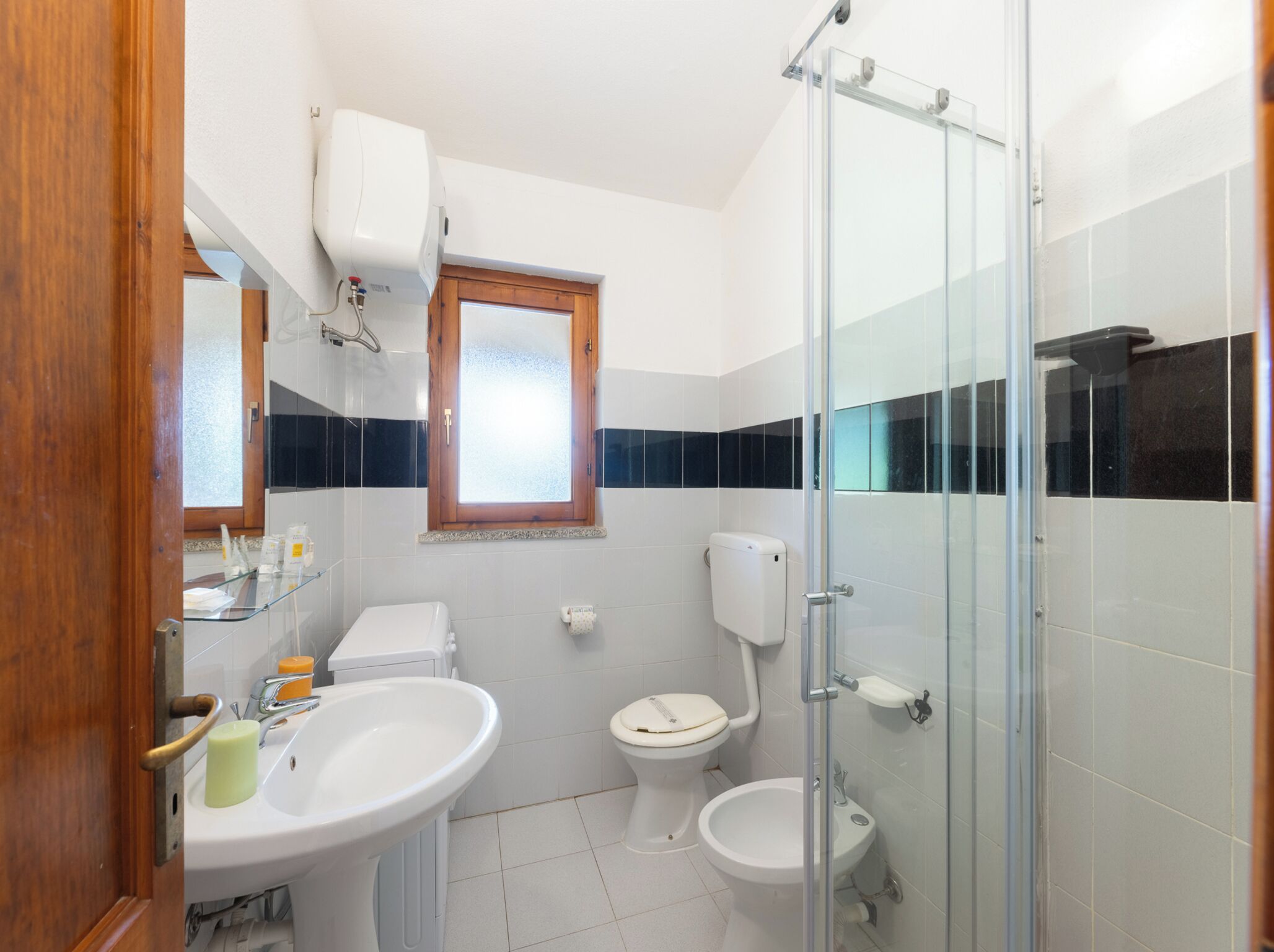 Un baño con inodoro, bidé, lavabo y cabina de ducha de vidrio.