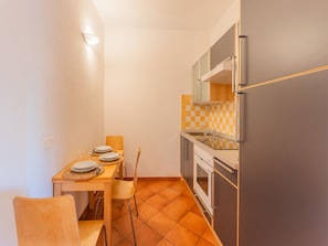 Cocina compacta con una mesa de comedor para dos personas, refrigerador, horno y microondas.