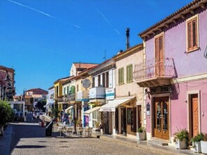 A cobblestone street lined with colorful buildings, some with balconies and storefronts. - Comfortable family accommodation (Santa Teresa Gallura)