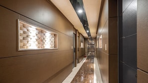 A modern hallway with a polished floor, recessed lighting, and a decorative brick wall. - Hotel Hue (Incheon)